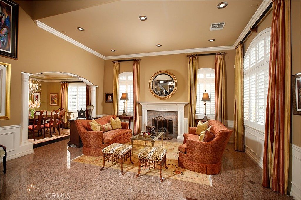 The formal living room anchored by a fireplace, draped windows, and granite flooring